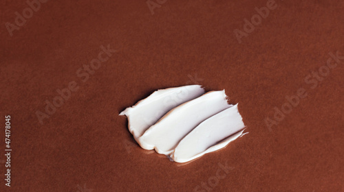 Smear of white face cream on brown background. Cosmetic product texture