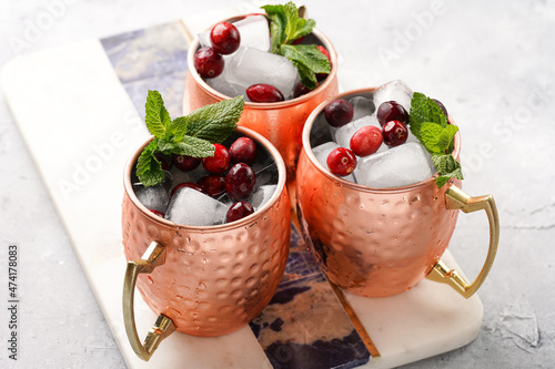 Traditional american alcoholic beverage moscow mule in copper mugs with cranberry and mint on white marble board - non-alcoholic cocktail version