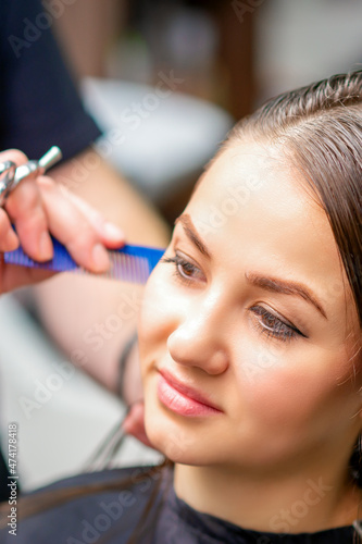 Styling female hair. Male hairdresser makes hairstyle for a young woman in a beauty salon