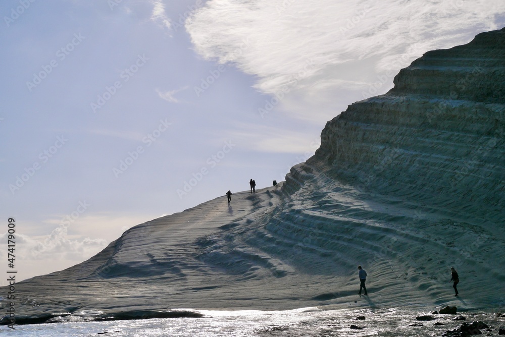 People walking on the white limestone stairs of Scala dei Turchi. Popular tourist attraction close to Agrigento, Sicily, Italy.