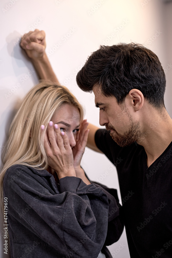 man attacks woman, domestic violence. Drunk husband beats wife. An aggressive man hits frightened female, crying. Pinned to the wall and scared. family domestic domination couple man attacks woman, domestic violence. Drunk husband beats wife. An aggressive man hits frightened female, crying. Pinned to the wall and scared. family domestic domination couple