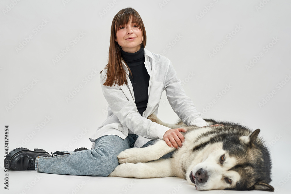 Adult caucasian woman touching Siberian Husky dog