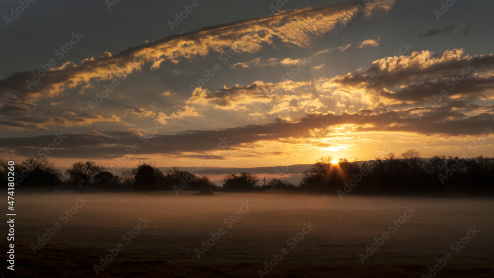 Sunrise panorama with cloudscape, sunbeams and fog