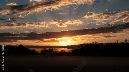 Beautiful sunrise with cloudscape sunbeams and fog © Tamara  Harding