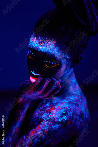 black fantastic woman Native American with neon makeup, made of fluorescent paint in ultraviolet light. fantasy, beauty, models, body art concept. isolated on dark background