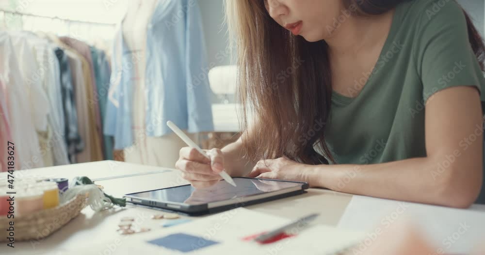 Close-up professional Asia female fashion designer with casual use digital tablet create new collection in her shop. Lady tailor study draw sketch on tablet pad site work at university studio. Close-up professional Asia female fashion designer with casual use digital tablet create new collection in her shop. Lady tailor study draw sketch on tablet pad site work at university studio.