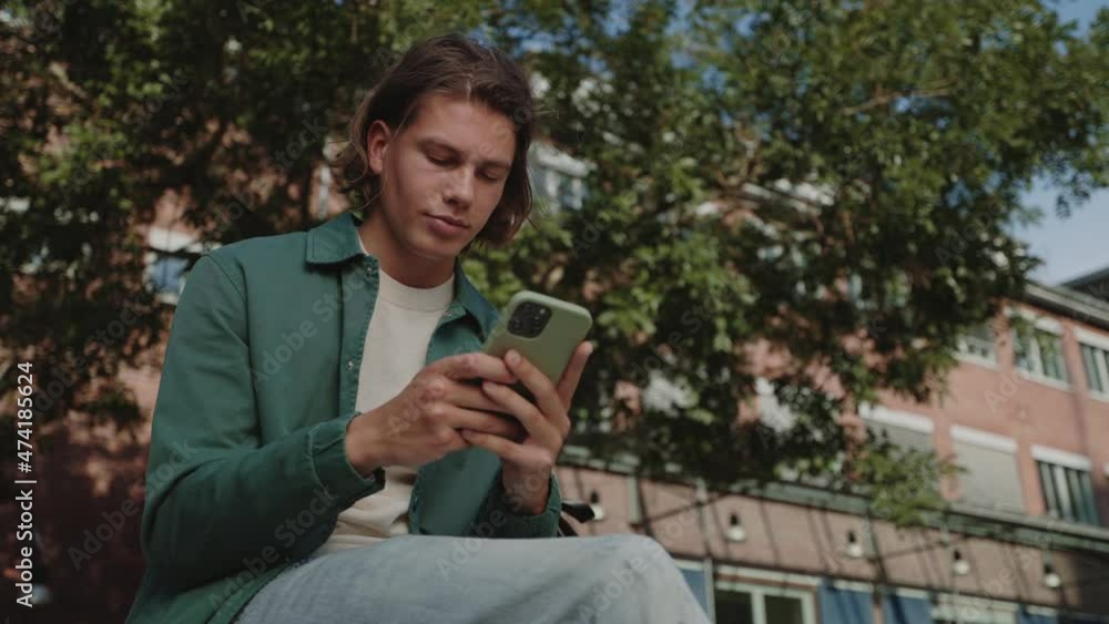 Male hipster sitting at urban area and using smartphone Male hipster sitting at urban area and using smartphone