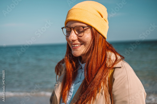 Portrait of positive woman 30s smiling while walking along seashore