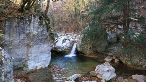 Waterfall among stones in a mountain river in an autumn forest