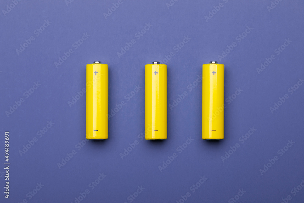 Yellow AA alkaline batteries on blue trendy color of 2022 background Yellow AA alkaline batteries on blue trendy color of 2022 background