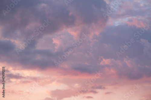 Moody sunset or sunrise sky with rays of light illuminating dark blue and bright and soft pink and orange clouds. no people, clouds only. High contrasts in a stormy sky © RoMaLi