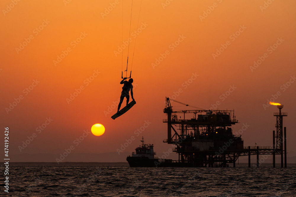Extreme Sport Kitesurfing against Offshore Jack Up Rig in The Middle of The Sea at Sunset Time
