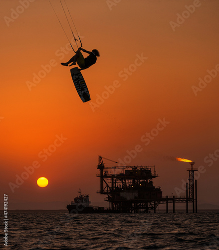 Extreme Sport Kitesurfing against Offshore Jack Up Rig in The Middle of The Sea at Sunset Time photo