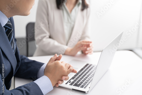 オフィスでノートパソコンを見ながら打ち合わせをする男女のビジネスマン手元