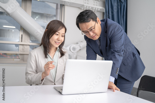オフィスでノートパソコンを見ながら打ち合わせをする男女のビジネスマン