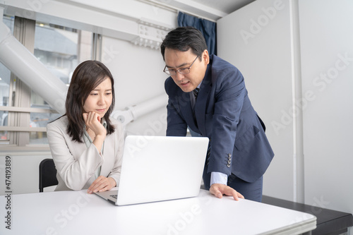 オフィスでノートパソコンを見ながら打ち合わせをする男女のビジネスマン