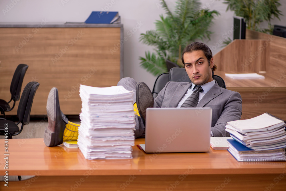 Young male employee and too much work in the office Young male employee and too much work in the office