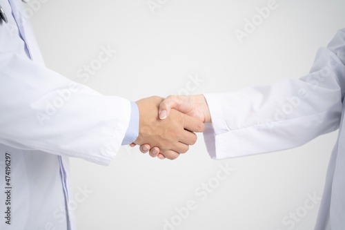 握手をする男女の白衣を着た医療従事者・手元アップ白背景
