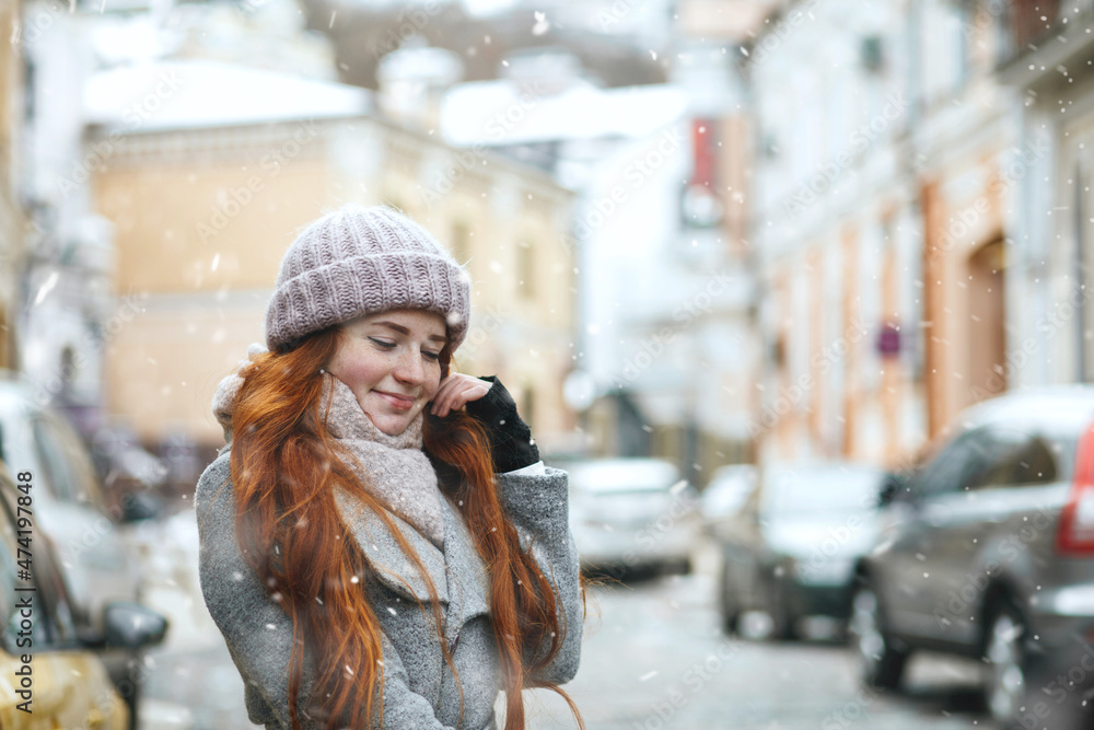 Fototapeta premium Stunning redhead lady walking at the city during new year vacation