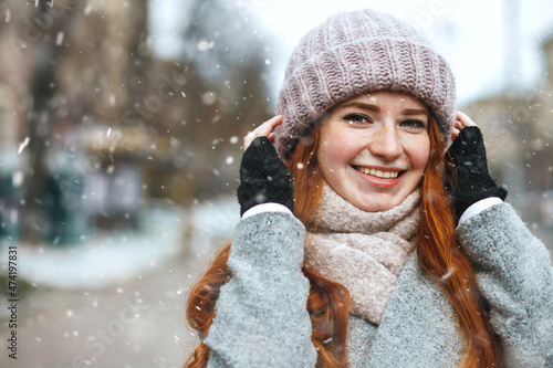 Fashionable ginger lady walking at the city with snowflakes