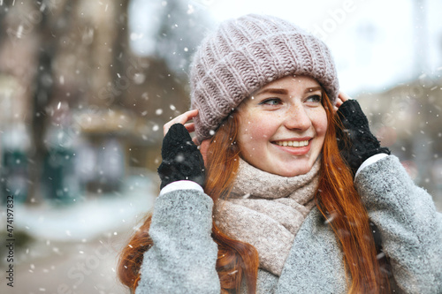 Elegant ginger lady walking at the city with snowflakes