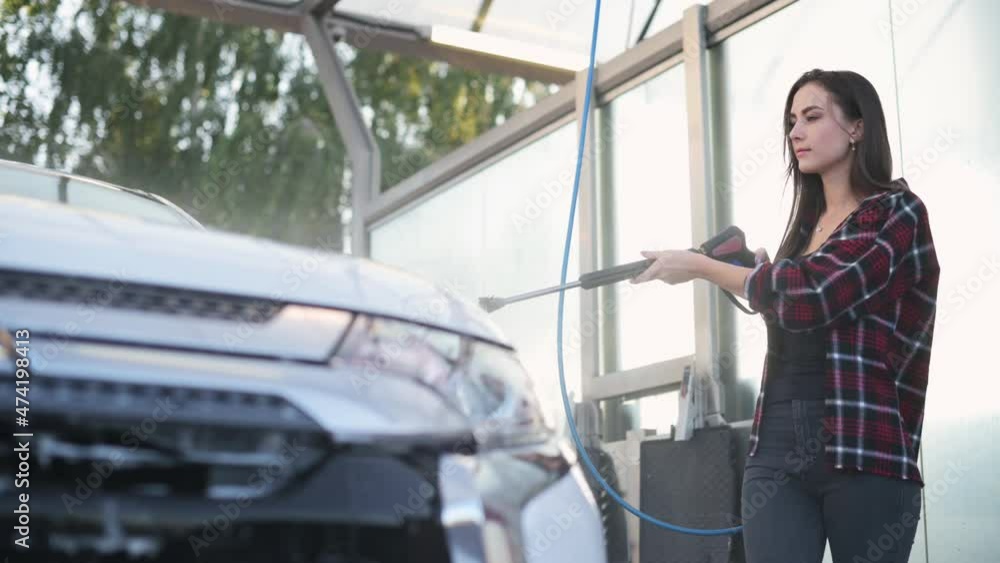 Self-service car wash. Young woman pouring water on her car. Self-service car wash. Young woman pouring water on her car.