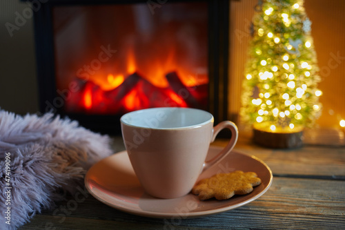 Cup with blanket over fireplace on wooden table. Winter and Christmas holiday concept