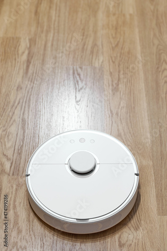 White robot vacuum cleaner on a laminate, rear view.