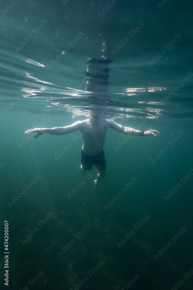Man swimming in a blue sea. Young man bathing and relaxing in the clear and transparent sea water.