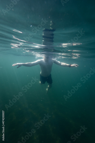 Man swimming in a blue sea. Young man bathing and relaxing in the clear and transparent sea water.