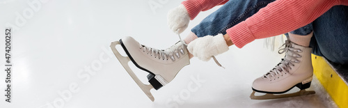 Fotografia cropped view of woman tying shoe laces on ice skates, banner.