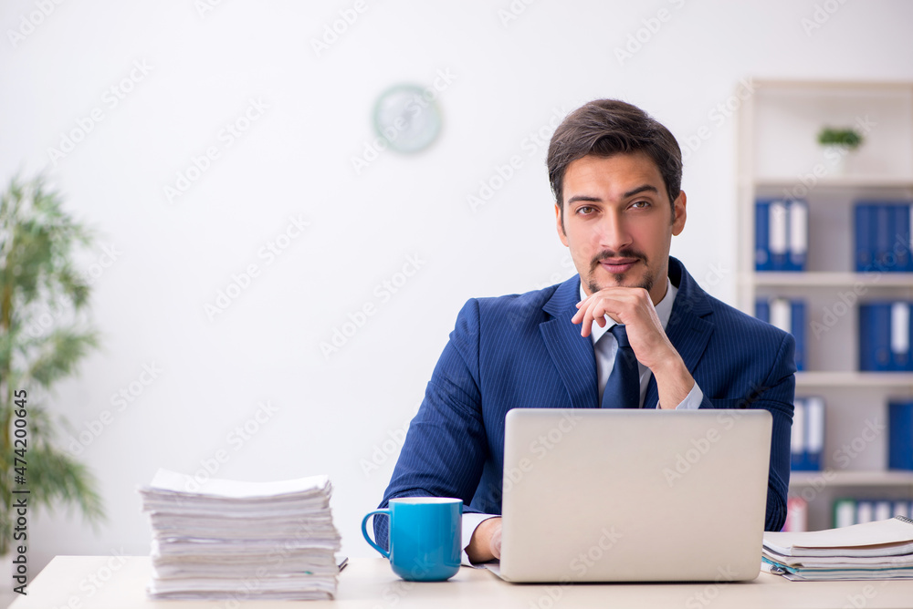 Young male employee and too much work in the office Young male employee and too much work in the office