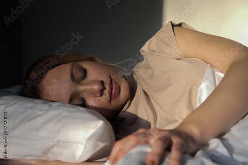 woman falling asleep in her white covered bed, young beautiful woman sleeping, 