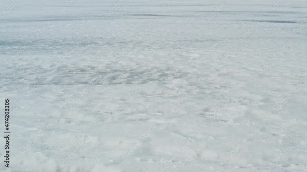 Aerial pan up to reveal endless frozen water. Winter landscape of frozen lake and alpine mountain. Aerial pan up to reveal endless frozen water. Winter landscape of frozen lake and alpine mountain.