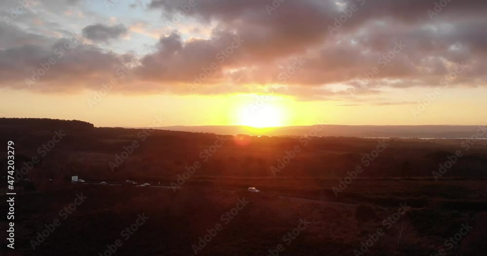 Rising aerial shot looking over busy road near Exmouth in Devon England with golden sunset in the background Rising aerial shot looking over busy road near Exmouth in Devon England with golden sunset in the background