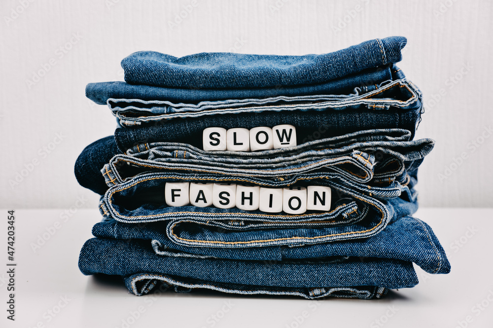 Slow fashion, second hand, Vintage Shopping, slow fashion, Sustainable  fashion concept. Stack of blue old denim jeans with the words slow fashion  Stock Photo | Adobe Stock