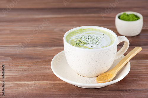 Matcha latte tea with coconut milk in a mug on a wooden table. Horizontal orientation, copy space.