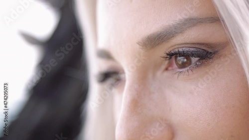 Blond young woman dressed as angel with black wings. Brown-eyed fashion female model. Extreme close-up.