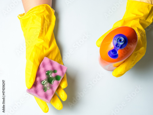 woman in yellow gloves pours dishwashing gel onto a sponge. housework in the kitchen. © Максим
