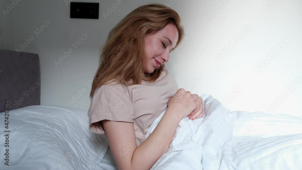 beautiful positive emotional woman getting up in bed stretching and smiling at camera beautiful positive emotional woman getting up in bed stretching and smiling at camera