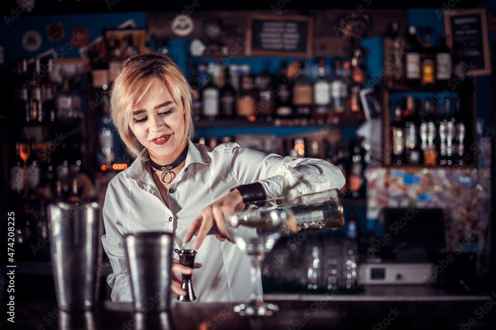 Girl bartender mixes a cocktail on the bar