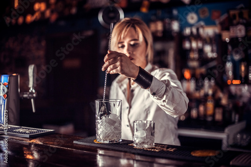 Focused woman barman decorates colorful concoction