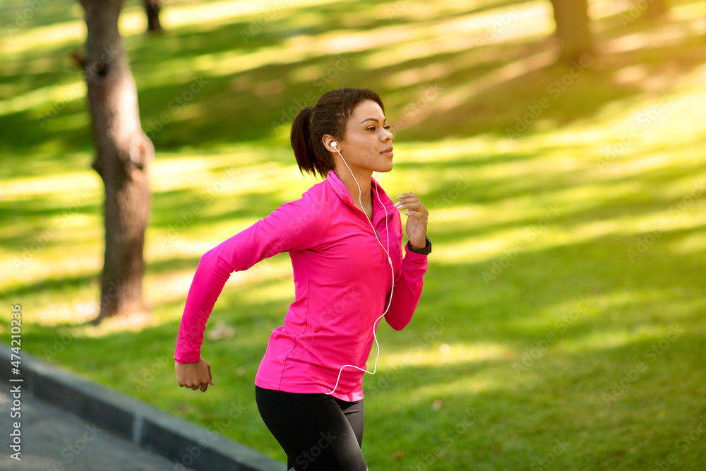 Side view of athletic black woman running by park Side view of athletic black woman running by park
