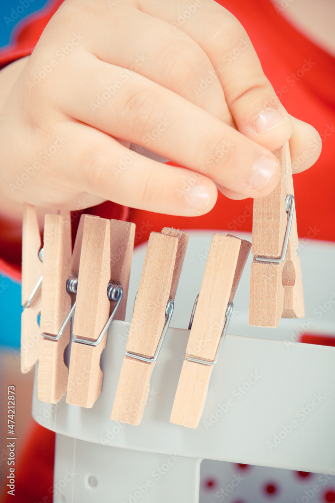 Little boy putting wooden clip on plastic box. Best creative game for early fine motor skills and coordination