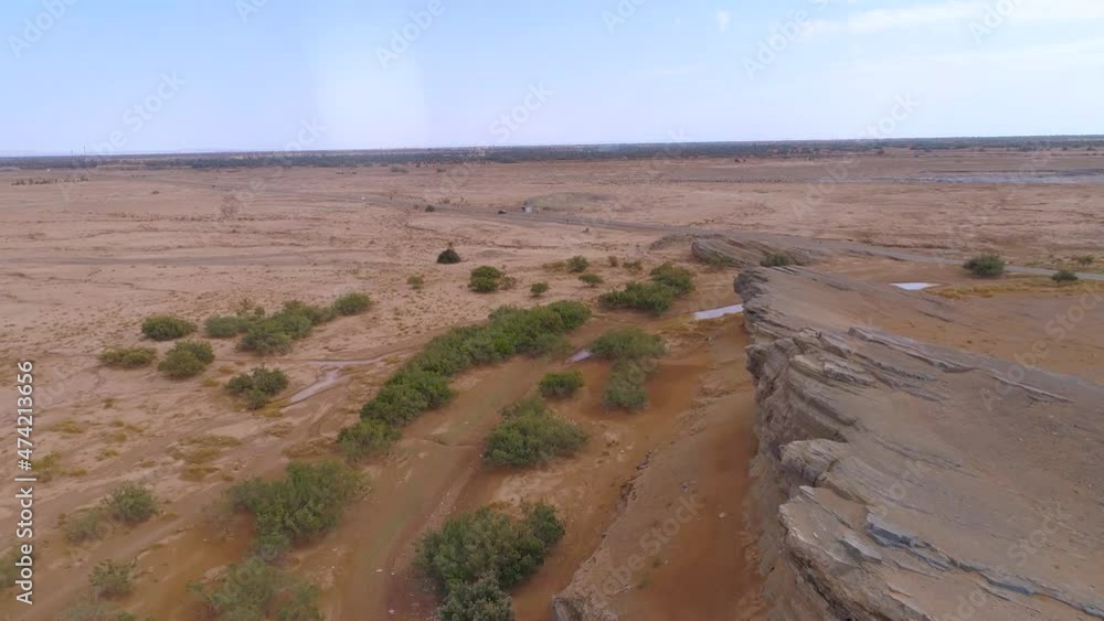 Aerial drone flight over dried landscape with few bush and trees growing in desert of Morocco - Small Creek with water during heat in africa Aerial drone flight over dried landscape with few bush and trees growing in desert of Morocco - Small Creek with water during heat in africa