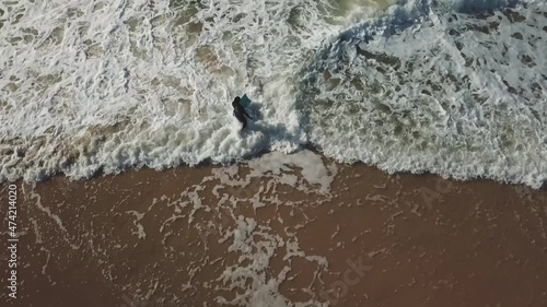 Bodyboard surfer entering the water at Capbreton beach in Western France, Aerial top view follow shot
