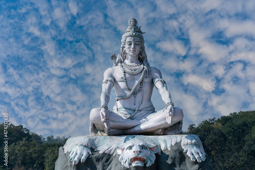 Fotografi Statue of meditating Hindu god Shiva against the sky and clouds on the Ganges Ri