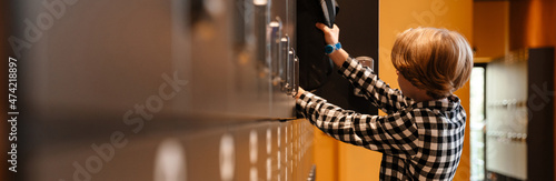 Konstfotografi White boy putting his backpack in checkroom at school