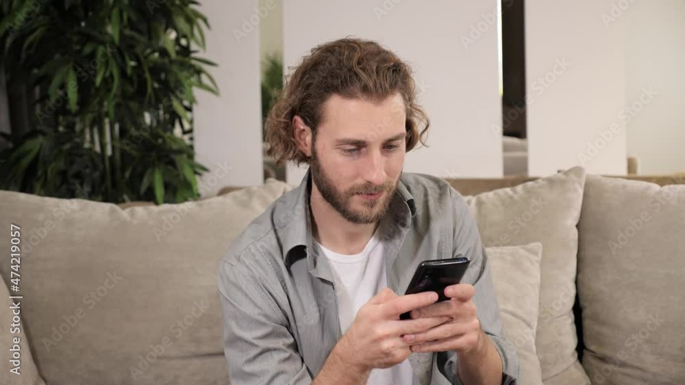 Close up relaxed positive man holding using smart phone watching social media sitting on sofa modern technology shopping online sale chatting with girl at home spend leisure time on internet. Close up relaxed positive man holding using smart phone watching social media sitting on sofa modern technology shopping online sale chatting with girl at home spend leisure time on internet.