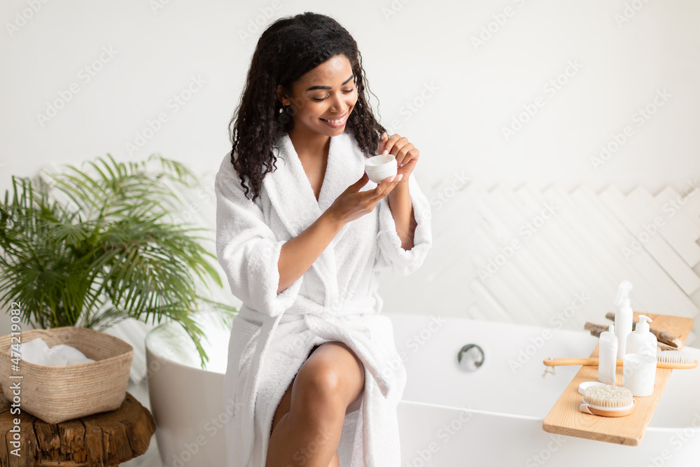 Black Lady Holding Moisturizer Cream Sitting On Bathtub In Bathroom Black Lady Holding Moisturizer Cream Sitting On Bathtub In Bathroom